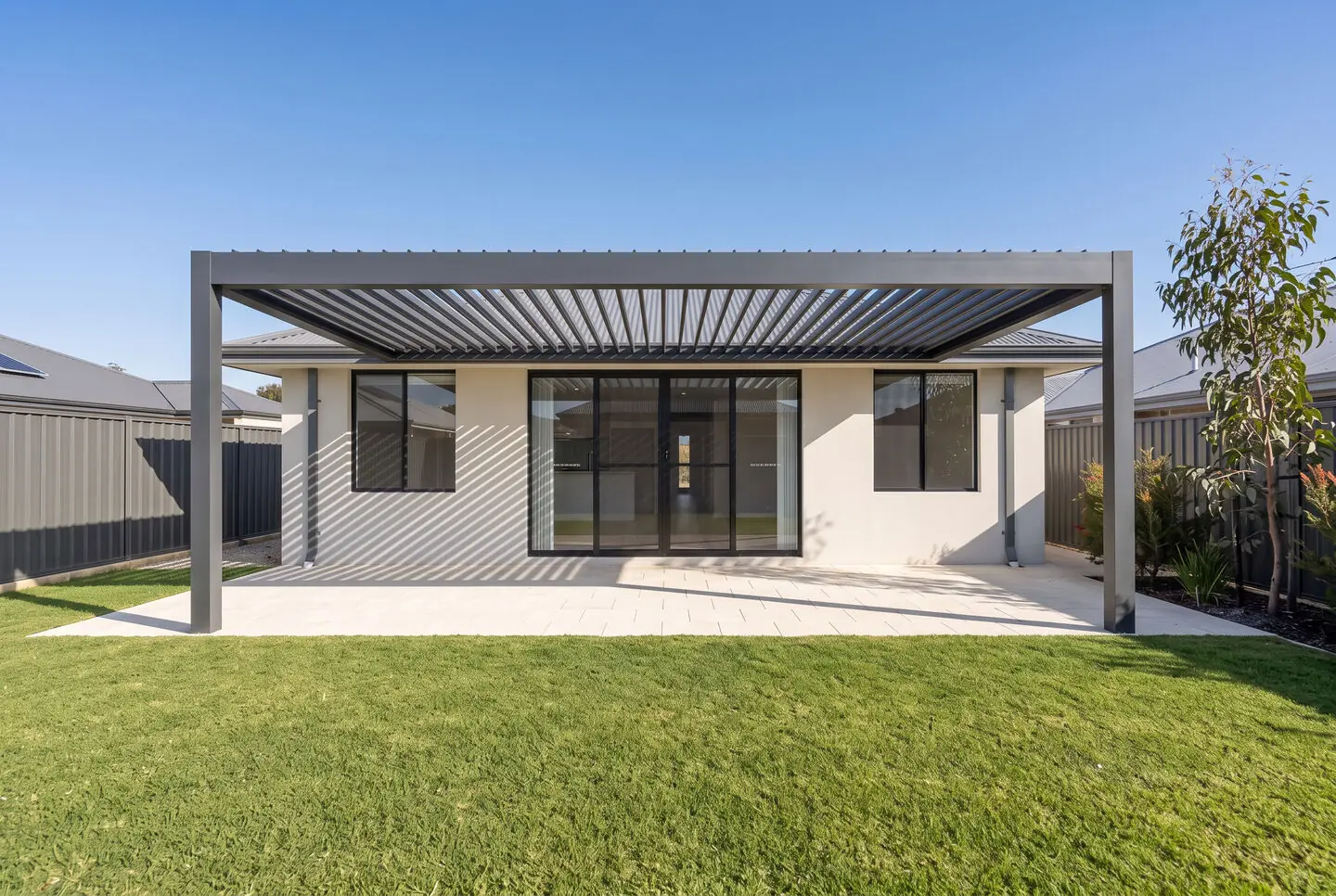 The same backyard with a charcoal adjustable louvre pergola